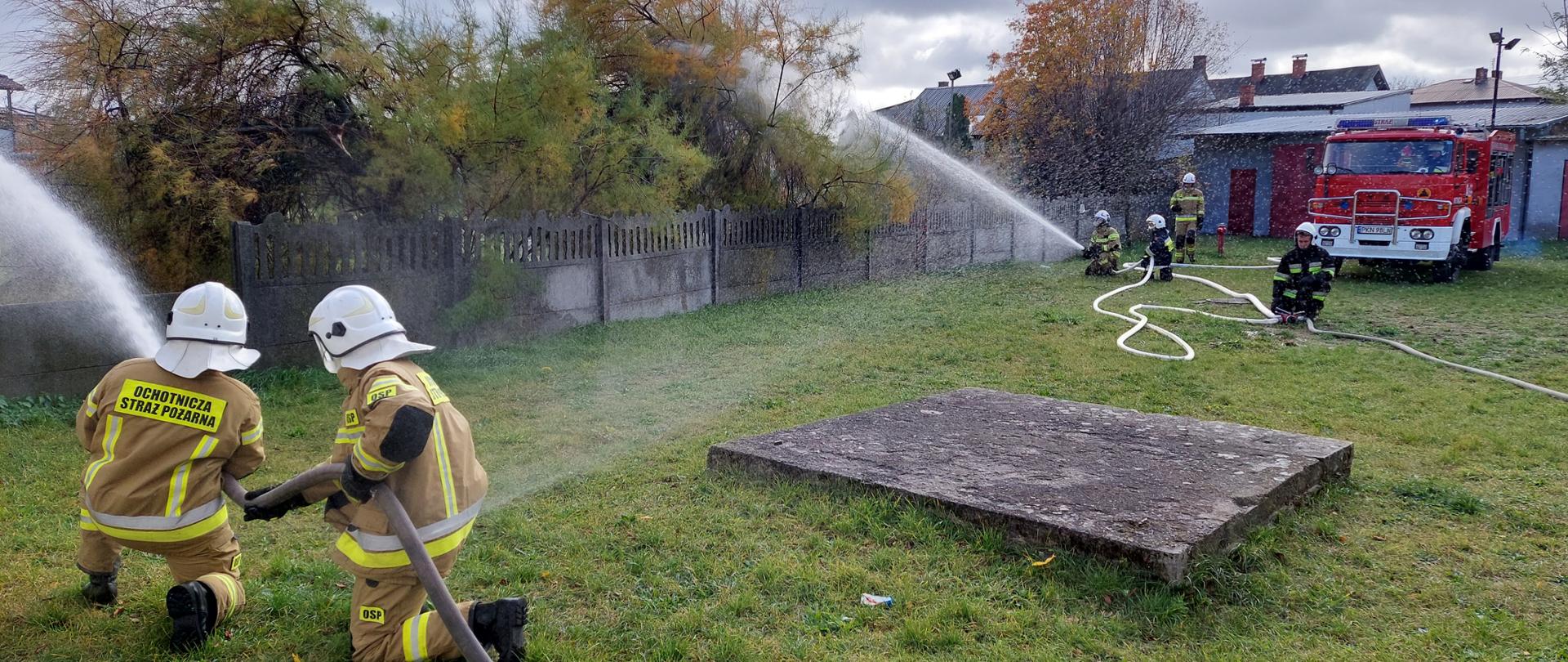 Zdjęcie przedstawia strażaków podczas szkolenia podstawowego. Druhowie podają wodę z dwóch linii gaśniczych. 