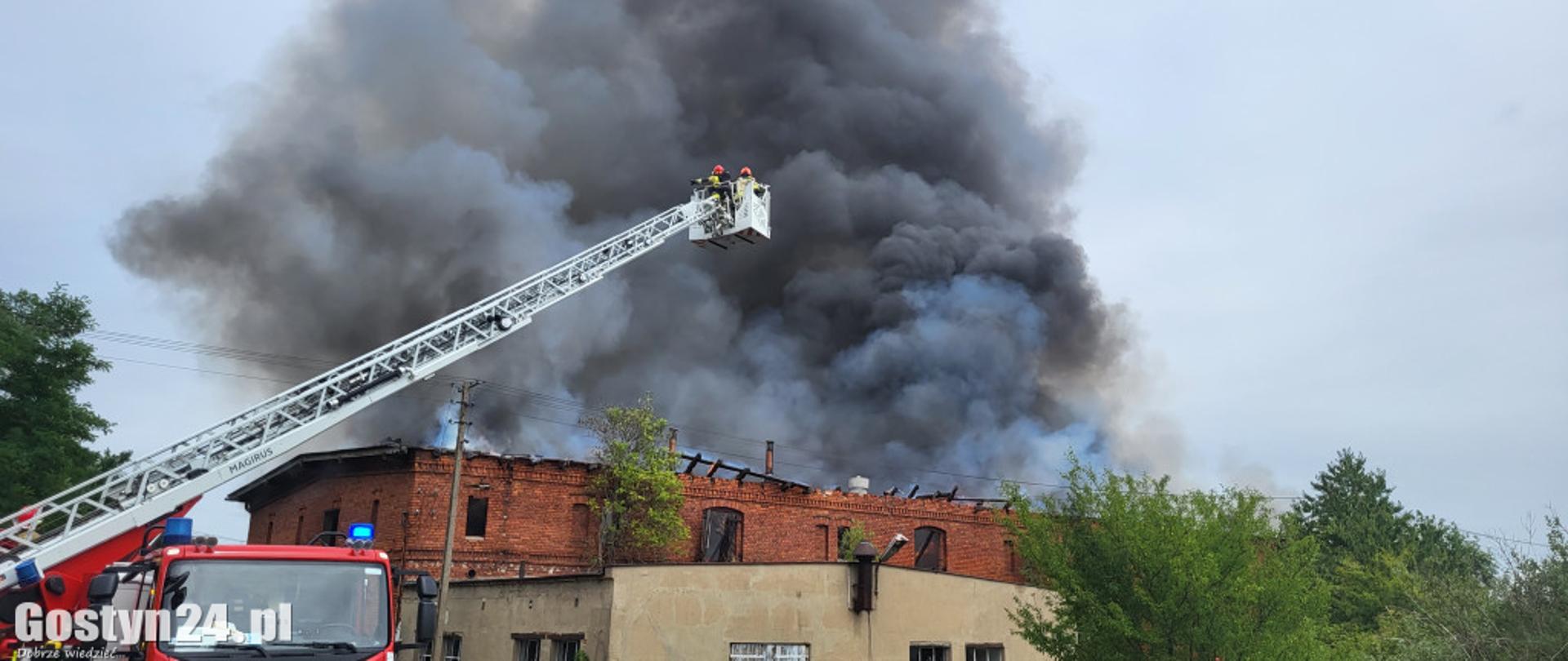 Zdjęcie przedstawia rozstawioną drabinę mechaniczną. W tle widać duży dym.