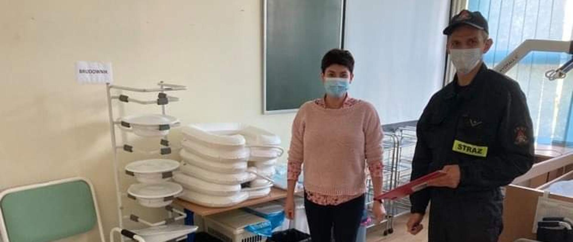 Zdjęcie ukazuje straża z KM PSP w Olsztynie w trakcie przekazywania płynów dezynfekcyjnych i maseczek
