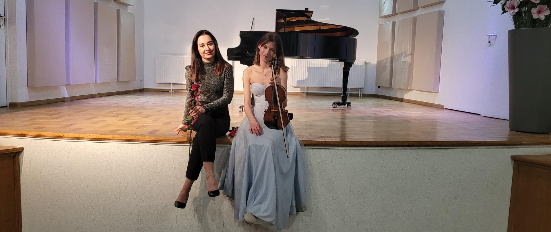 Zdjęcie przedstawia skrzypaczkę i pianistkę siedzące na scenie. 