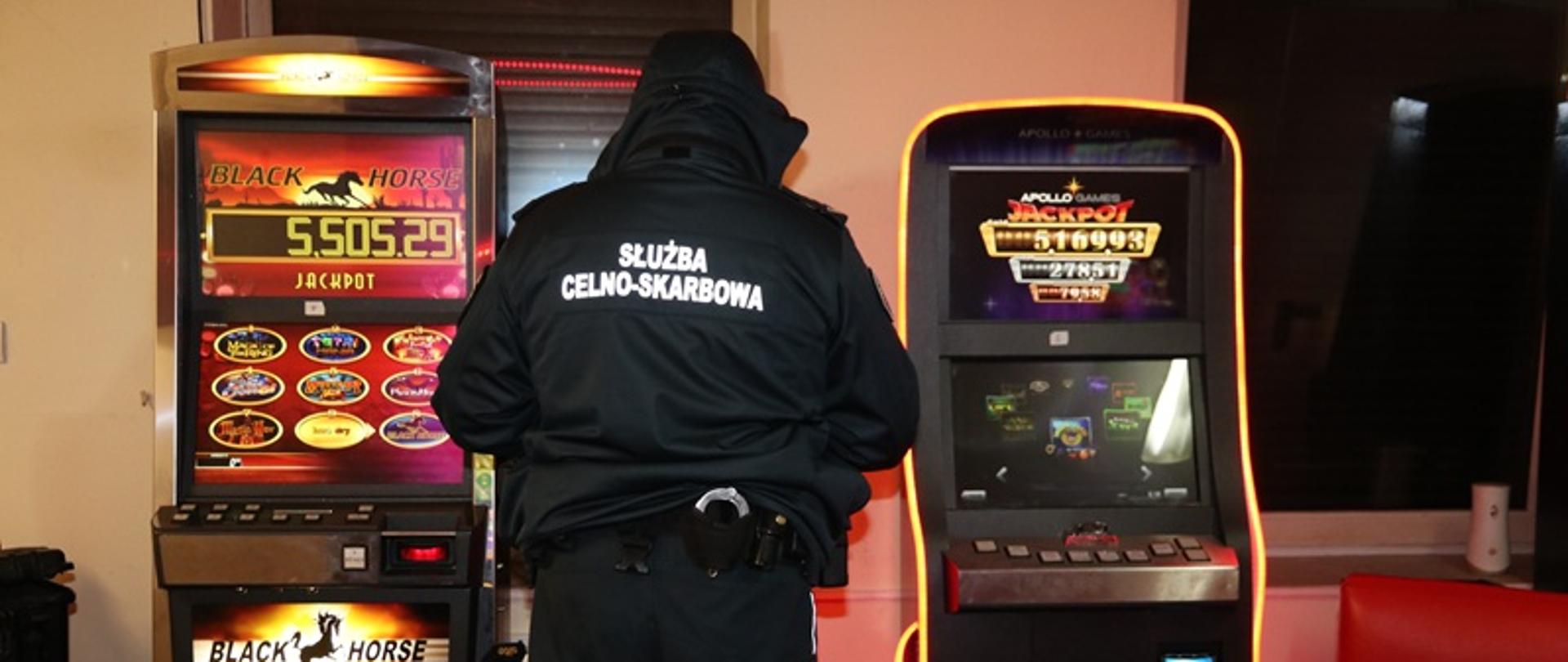 Funkcjonariusz stoi przed automatami do gier hazardowych.