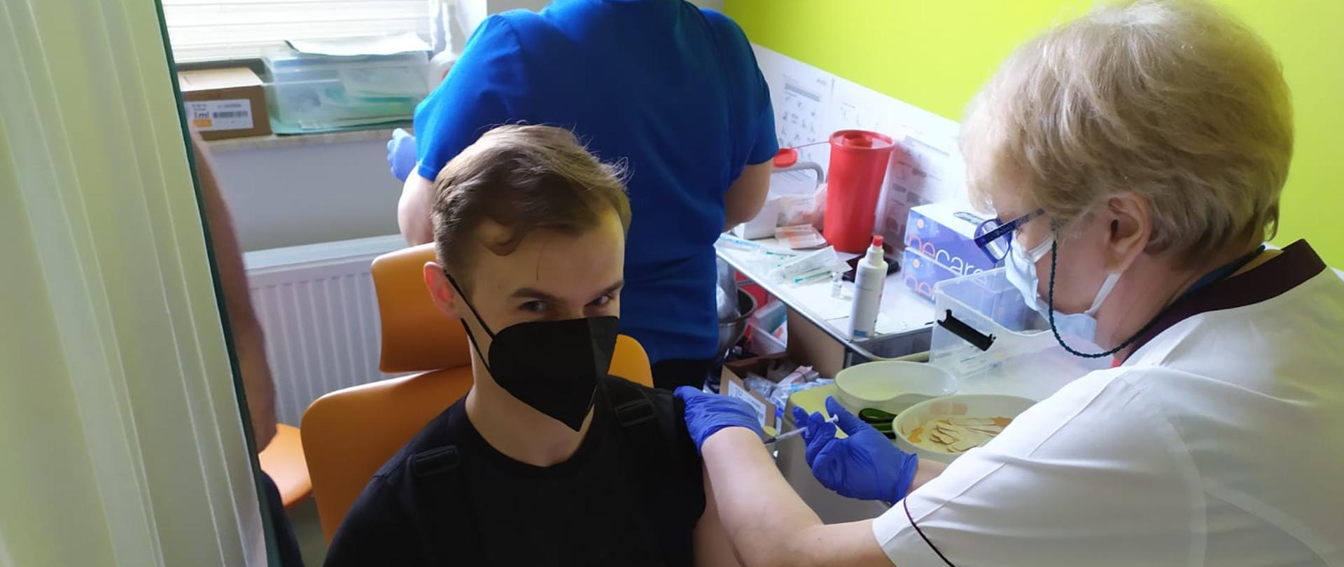 Na zdjęciu strażak jest szczepiony przeciwko COVID-19