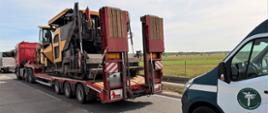 Od lewej: ciągnik siodłowy z podpiętą naczepą – platformą niespodwoziową. Zestaw przewozi dwie maszyny drogowe - walec drogowy i rozściełacz asfaltu. Za zatrzymanym do kontroli zespołem pojazdów stoi oznakowany furgon mazowieckiej Inspekcji Transportu Drogowego.