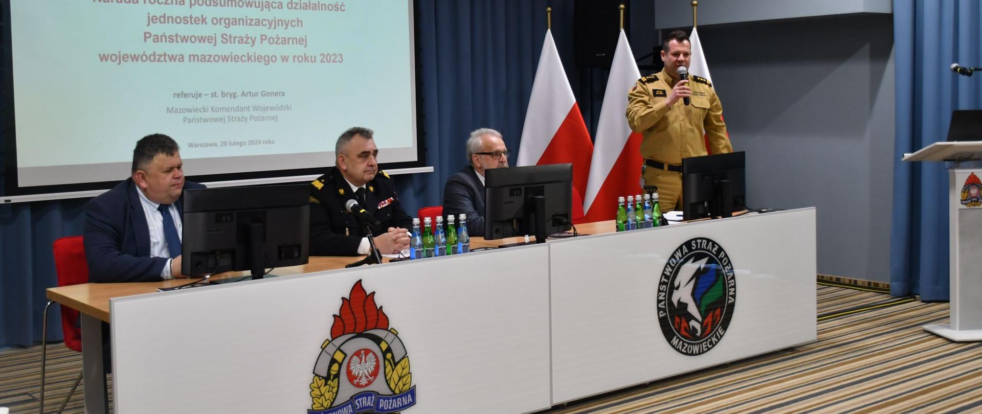 Zastępca komendanta głównego PSP podczas rozpoczęcia narady rocznej siedzi przy stole prezydialnym