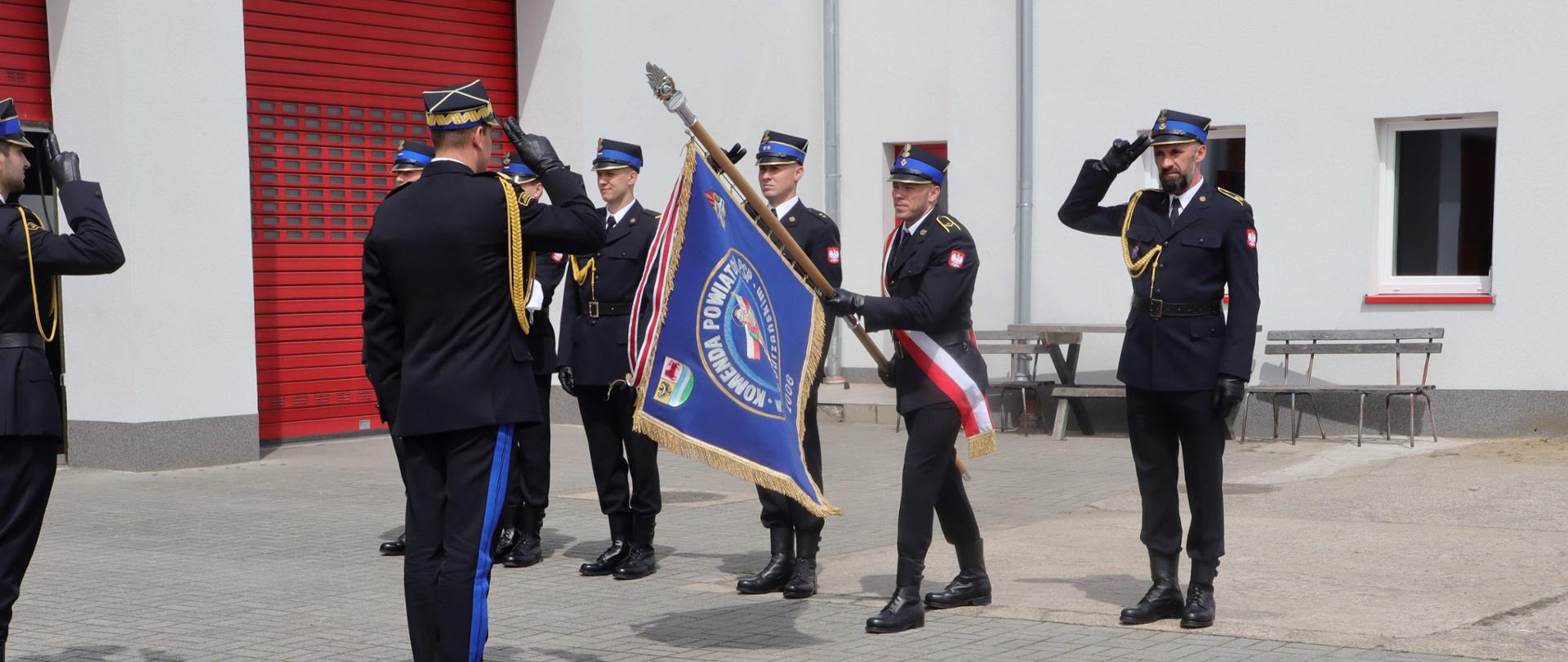 Zdjęcie przedstawia nadbryg. Patryka Maruszaka – Lubuskiego Komendanta Wojewódzkiego Państwowej Straży Pożarnej oddającego honory na sztandar Komendy Powiatowej Państwowej Straży Pożarnej w Krośnie Odrzańskim.