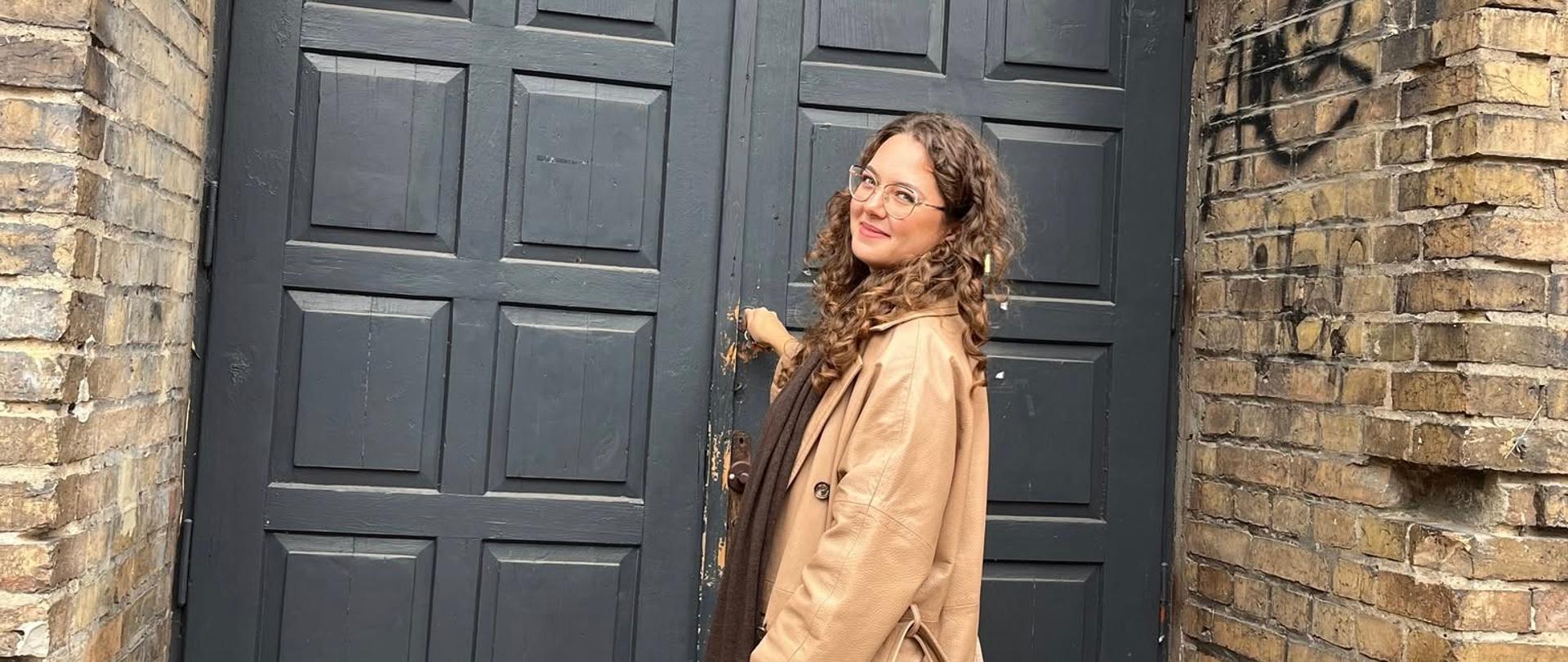 Kobieta otwierająca drzwi starego ceglanego budynku