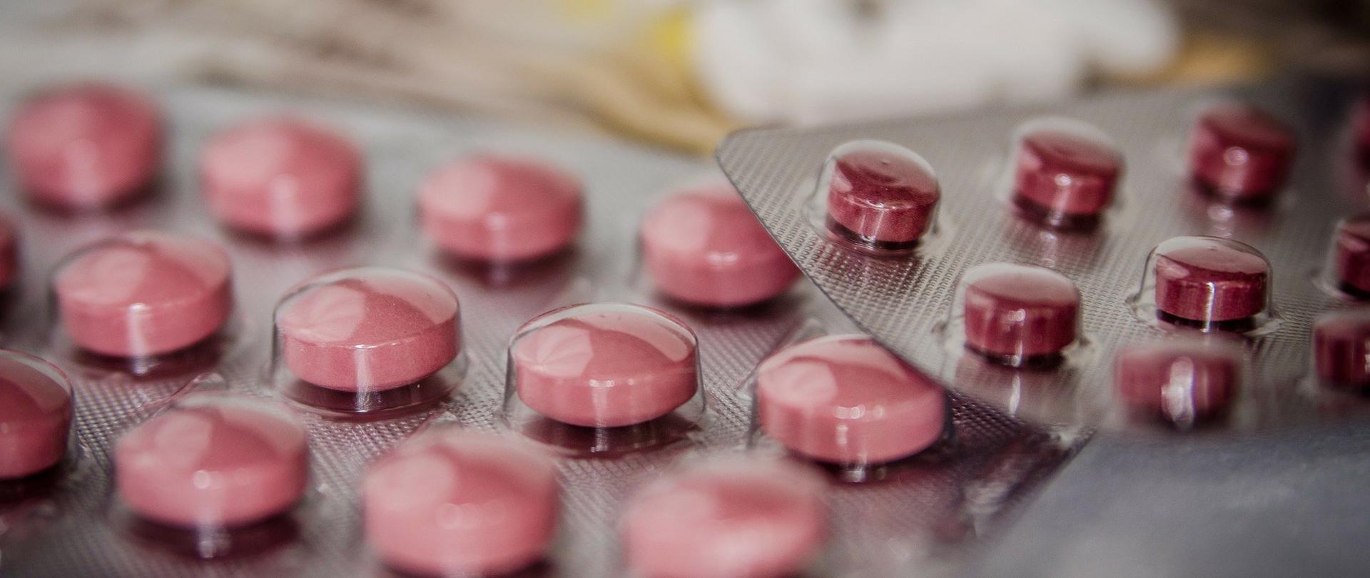 blistry z różowymi i czerwonymi tabletkami.