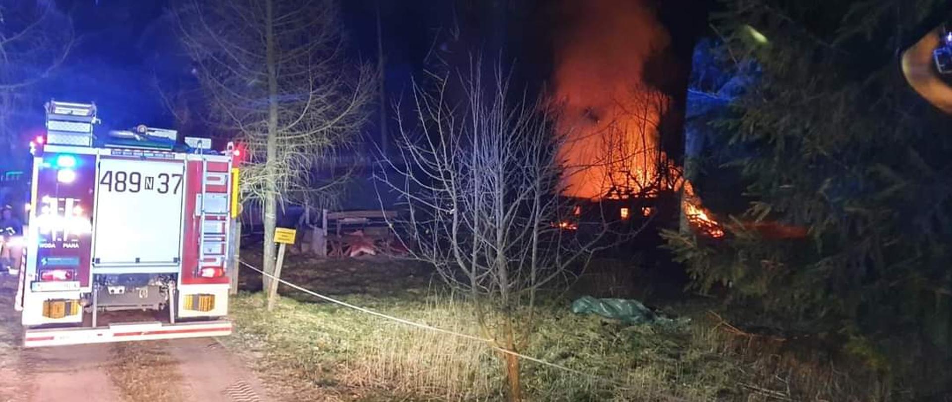 Pojazdy pożarnicze podczas dojazdu do pożaru w Bieniewie. Zdjęcie przedstawia rozwinięty pożar budynku gospodarczo-garażowego