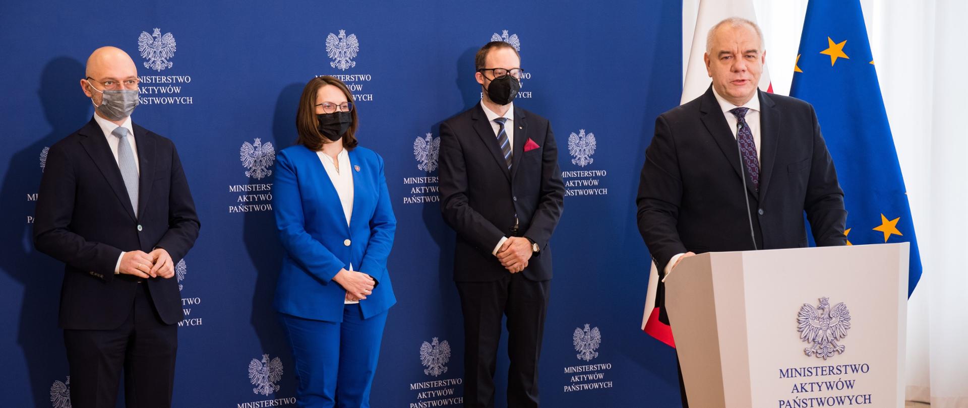 Wicepremier Jacek Sasin przemawia z mównicy. Z tyły stoją Minister Michał Kurtyka, Prezes Marek Dietl, Minister Magdalena Rzeczkowska.