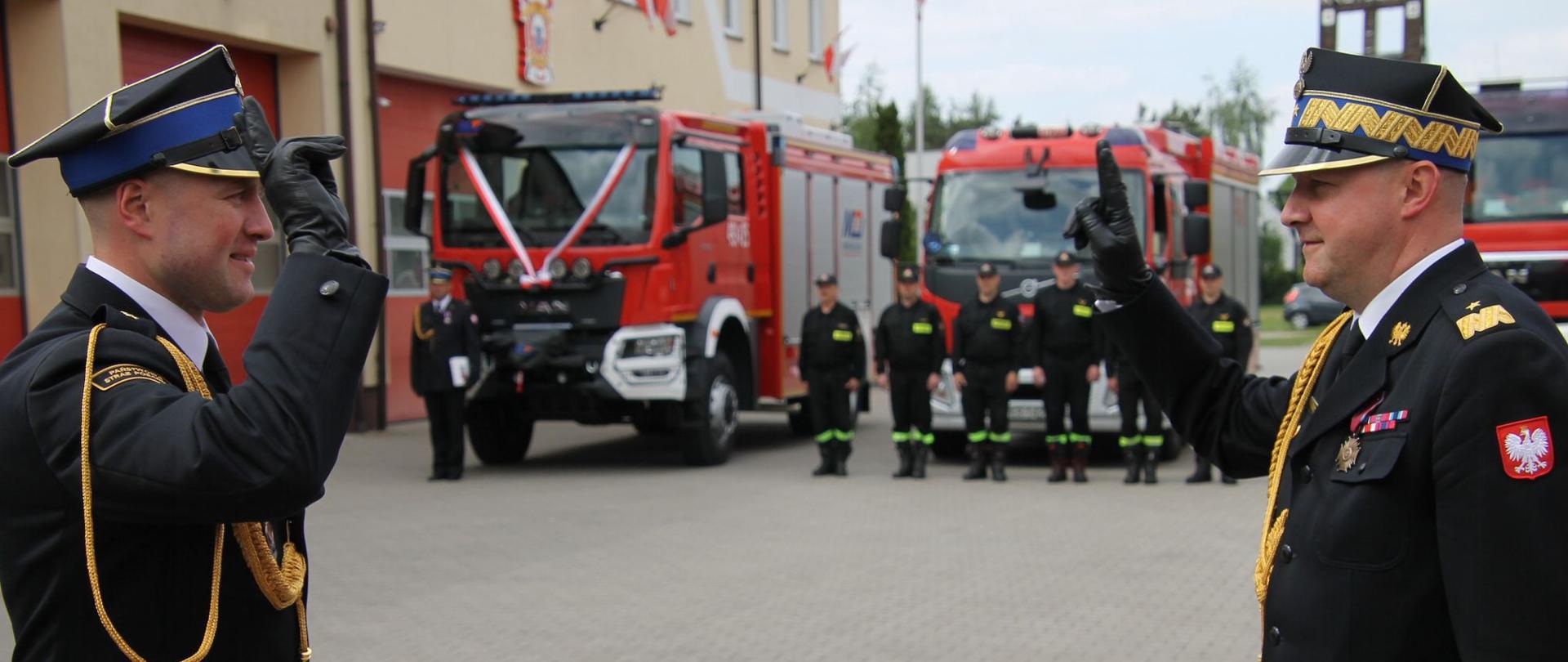Zdjęcie przedstawia Dowódcę Uroczystości oddającego honor Wielkopolskiemu Komendantowi PSP. w tle pojazdy pożarnicze.