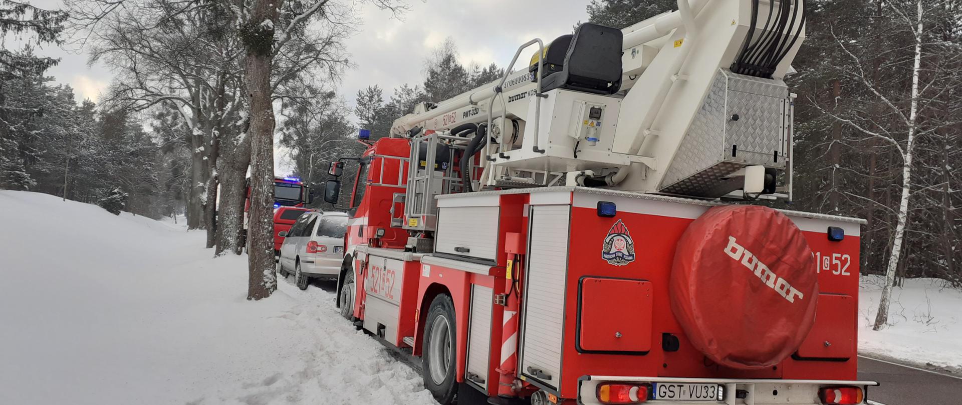 foto przedstawia samochody pożarnicze ustawione wzdłuż drogi dojazdowej na miejscu akcji