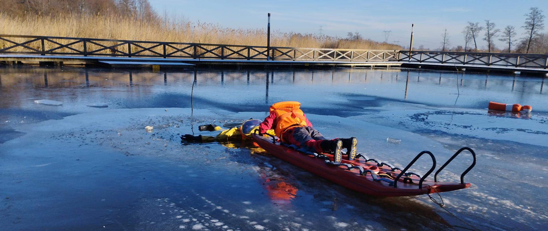 strażak na saniach lodowy na akwenie wodnym ratuje tonącego