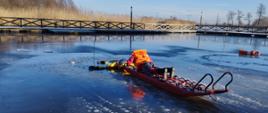 strażak na saniach lodowy na akwenie wodnym ratuje tonącego