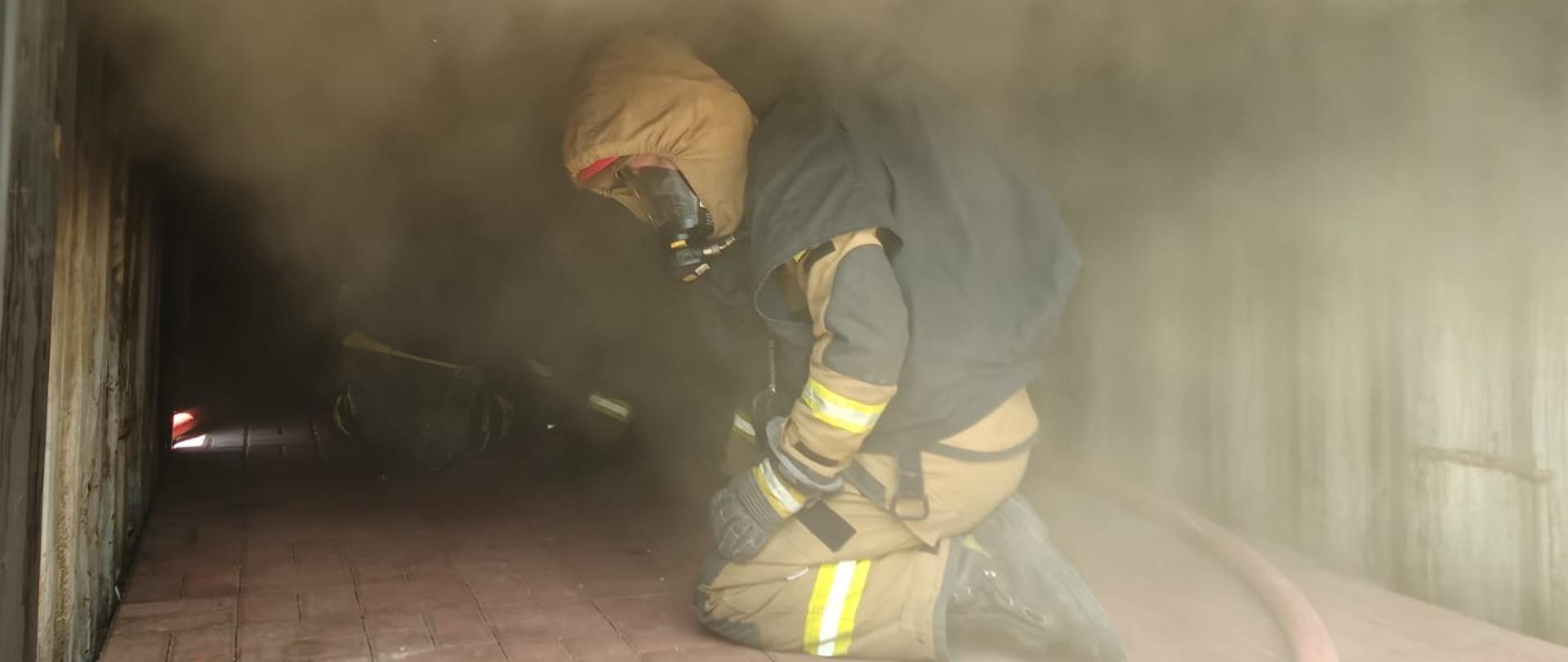 strażak w ubraniu specjalnym z sprzętem ochrony układu oddechowego w zadymionym kontenerze