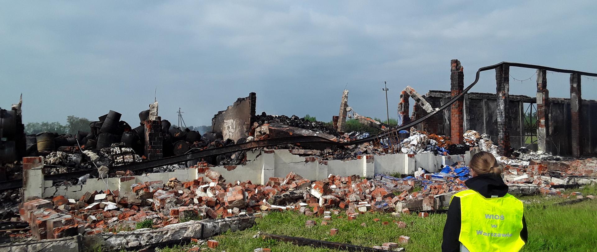 Inspektor Wojewódzkiego Inspektoratu Ochrony Środowiska w Warszawie kontroluje pogorzelisko po spalonym budynku magazynowym.