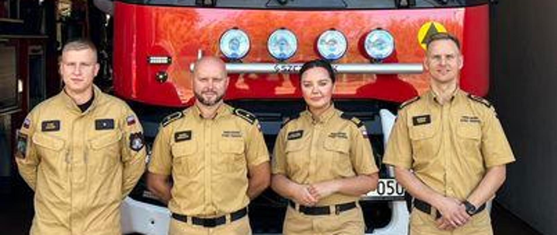 Funkcjonariusze KW PSP w Białymstoku i KM PSP w Białymstoku na tle samochodu pożarniczego