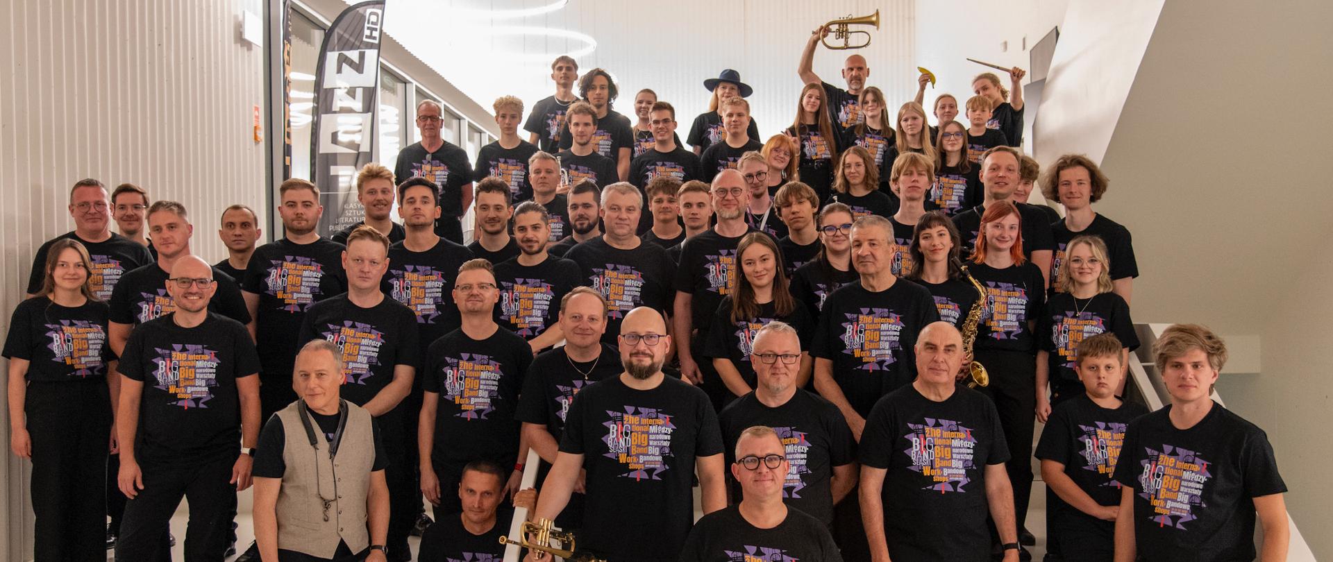 Wszyscy uczestnicy warsztatów stoją na schodach we foyer sali koncertowej.