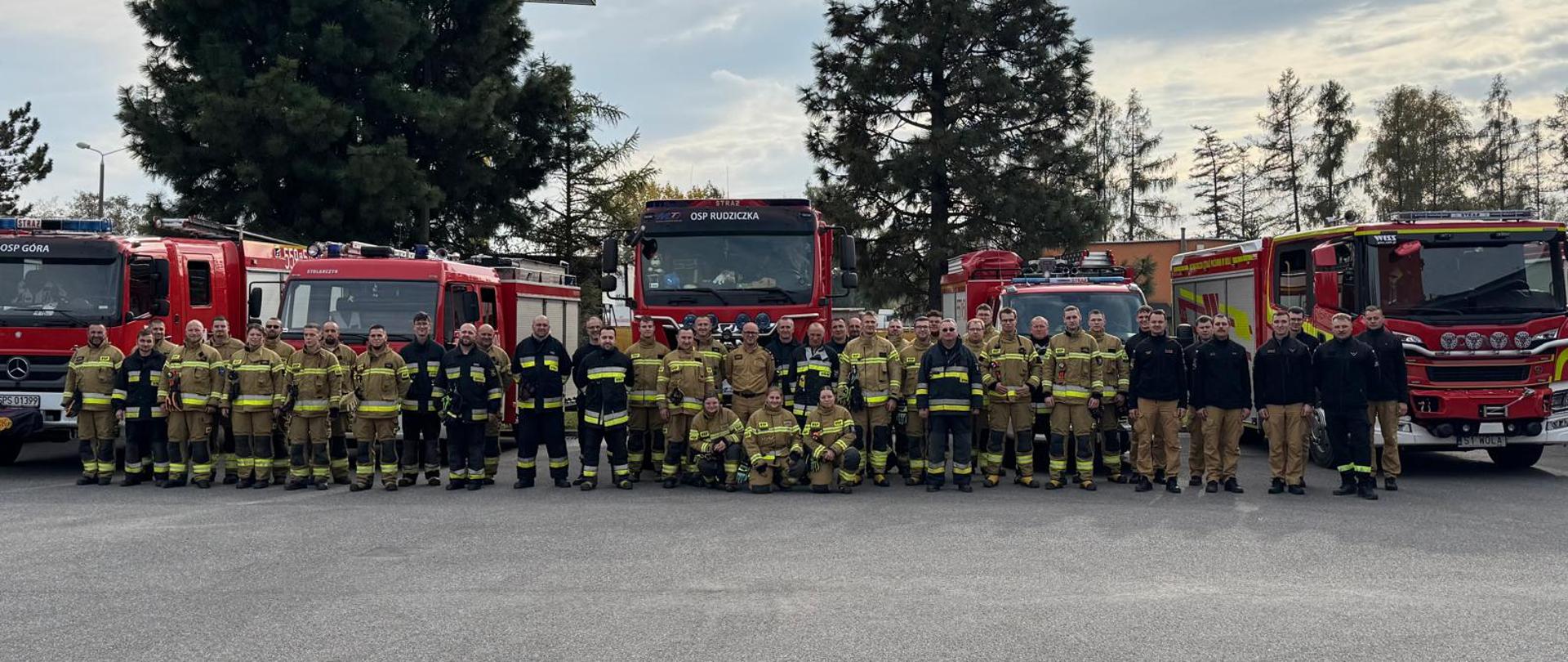 Strażacy OSP i PSP wraz z pojazdami pożarniczymi na placu zewnętrznym Komendy