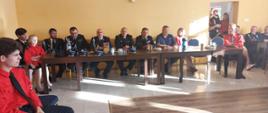 Na zdjęciu widać druhów OSP i komendanta powiatowego PSP w Ustrzykach Dolnych siedzących przy stole.