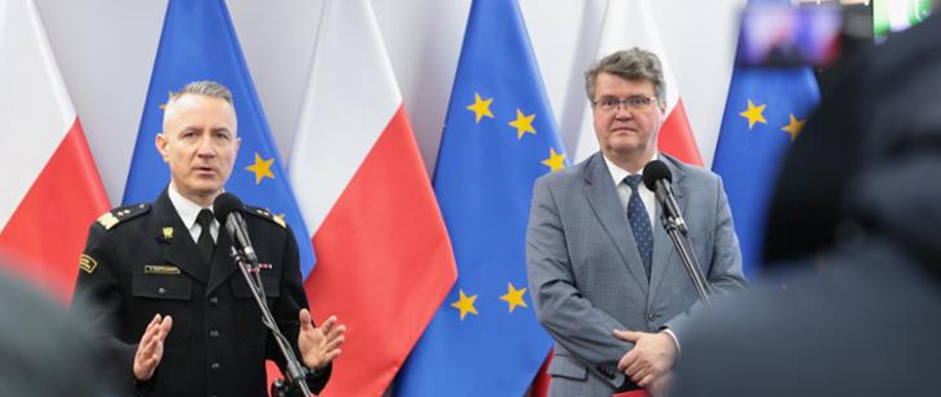 Minister mswia z Komendantem Głównym PSP na tle flag Polski i Unii Europejskiej