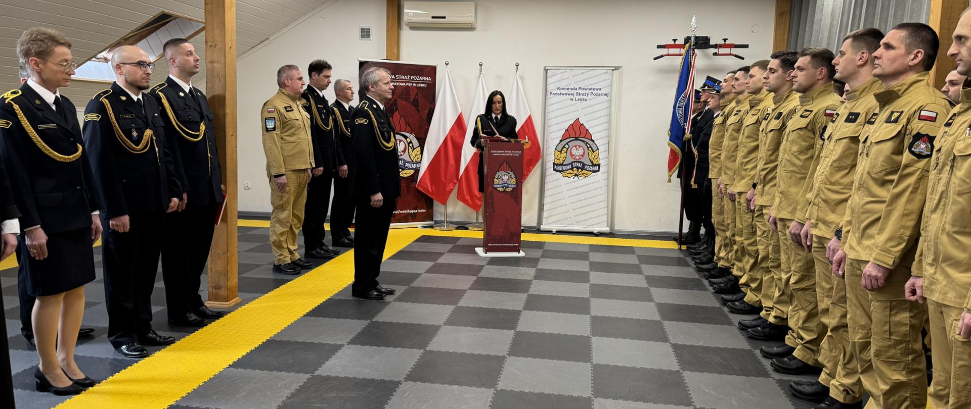 Zdjęcie przedstawia funkcjonariuszy i pracowników cywilnych KP PSP w Lesku podczas uroczystego apelu z okazji przejścia na zaopatrzenie emerytalne asp. sztab. Marka Szatkowskiego.