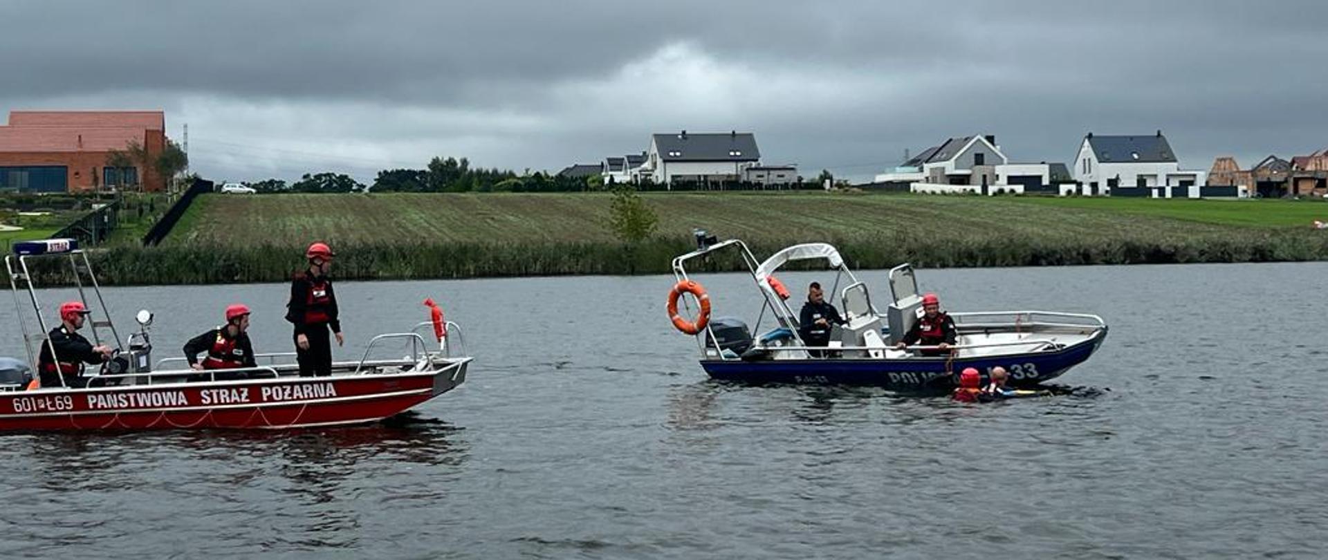 Na zdjęciu łódź strażacka oraz policyjna, w wodzie ratownik zabezpieczający osobę poszkodowaną