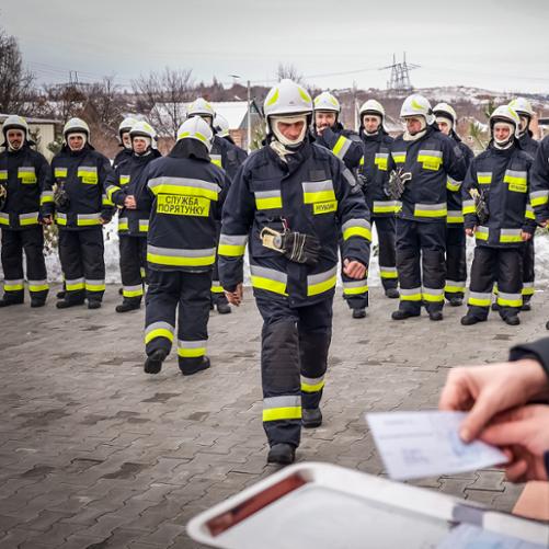 z grupy strażaków, wychodzi jeden i zmienia w kierunku obiektywu