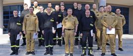 Grupowe zdjęcie uczestników szkolenia (16 funkcjonariuszy PSP) w towarzystwie Zastępcy Komendanta Centralnej Szkoły PSP oraz dwóch funkcjonariuszy CS PSP