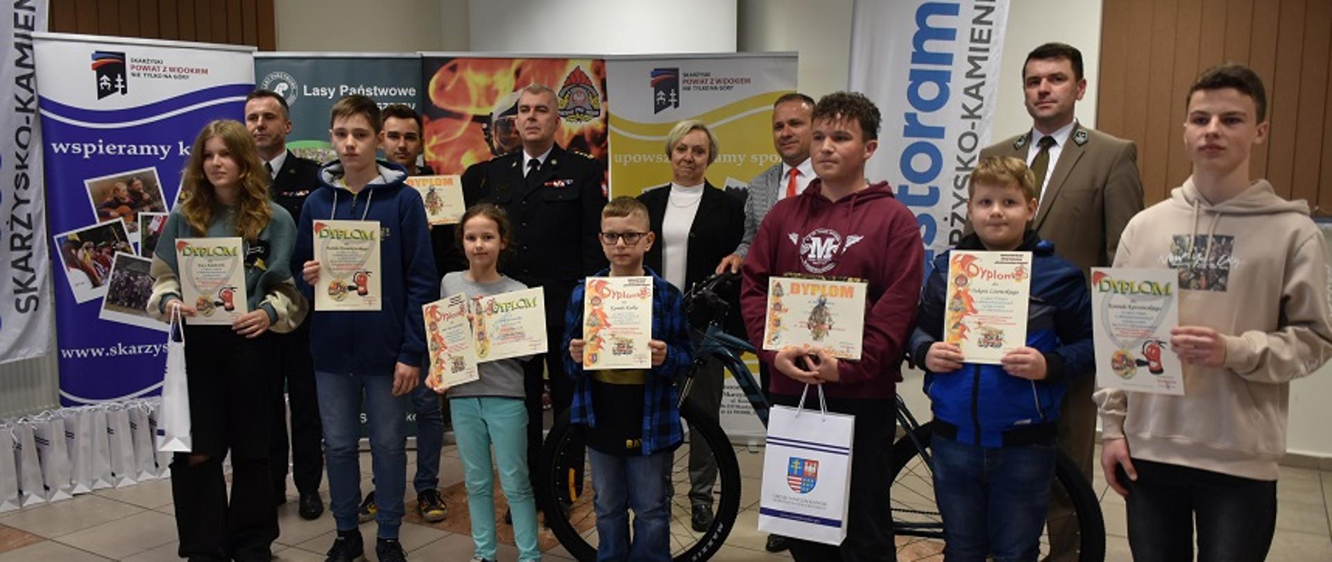 Zdjęcie obrazuje zwycięzców eliminacji powiatowego Ogólnopolskiego Turnieju Wiedzy Pożarniczej. Na zdjęciu widać dziesięcioro dzieci wraz z otrzymanymi nagrodami. 