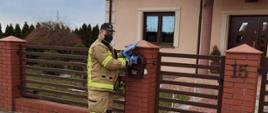 Widać strażaka z dostarczaną ulotką przy wejściu