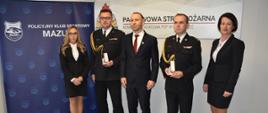 Odznaczeni i przedstawiciele Policyjnego Klubu Sportowego Mazury stoją do pamiątkowego zdjęcia.