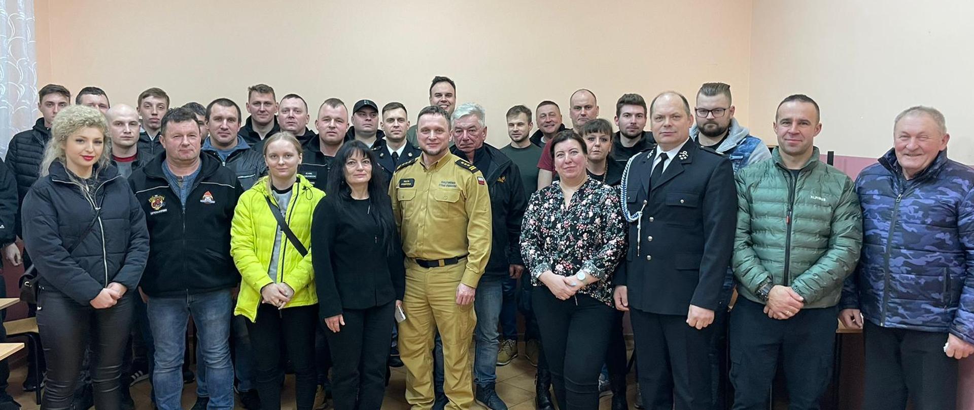 W pomieszczeniu w kilku szeregach stoi kilkadziesiąt osób.