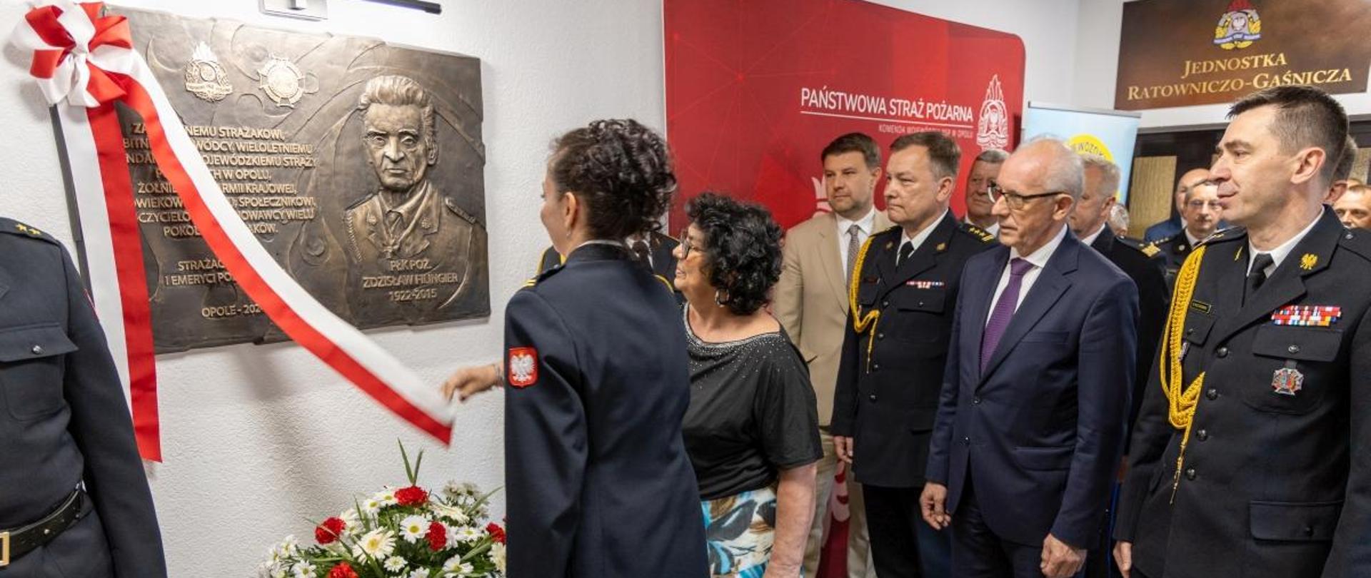 Tablicę pamiątkową odsłania Pani Joanna Biesiada córka oraz mł. bryg. Katarzyna Linette-Granat wnuczka pułkownika w obecności między innymi Pana Wiesława Leśniakiewicza Podsekretarza Stanu MSWiA, nadbryg. dr inż. Mariusza Feltynowskiego Komendanta Głównego PSP oraz st. bryg. Pawła Kielara Opolskiego Komendanta Wojewódzkiego PSP.