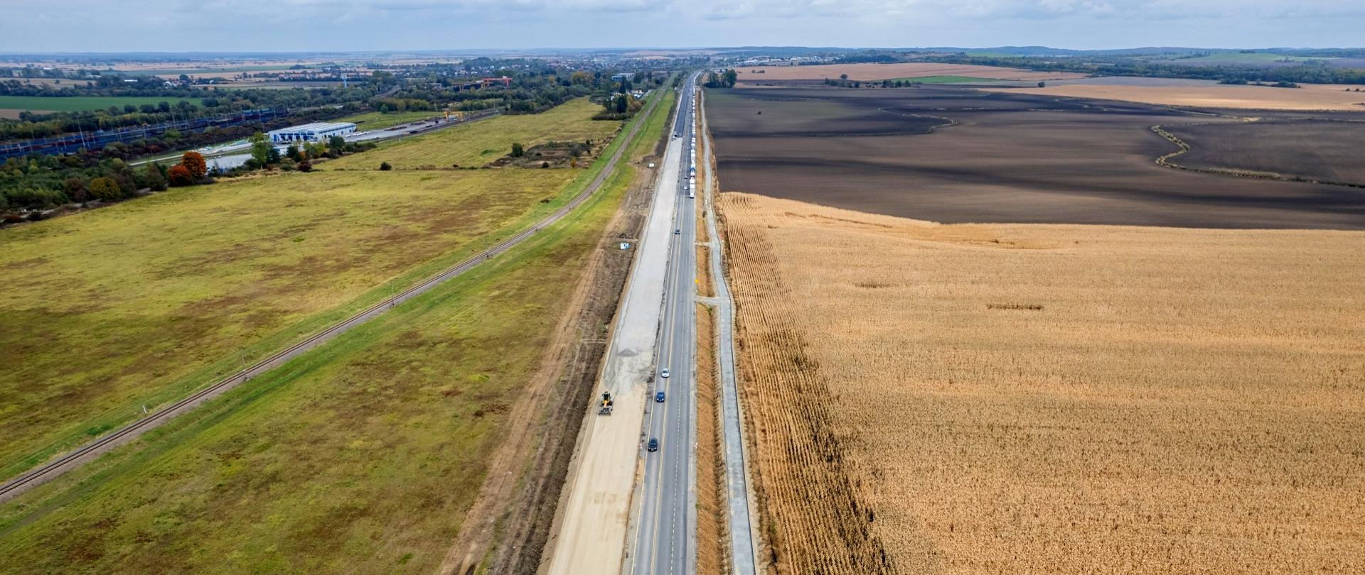 Widok z lotu ptaka na drogę krajową nr 28. Na prawej stronie jezdni odbywa się ruch pojazdów, natomiast na lewej stronie trwają prace budowlane. 