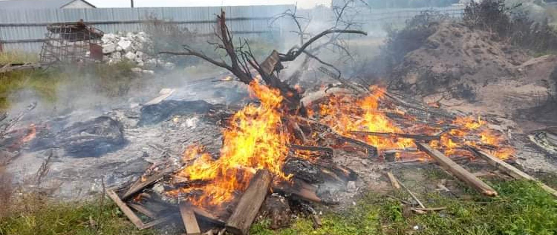 W centralnej części widać palące się palety i wytłaczanki. W tle płot.