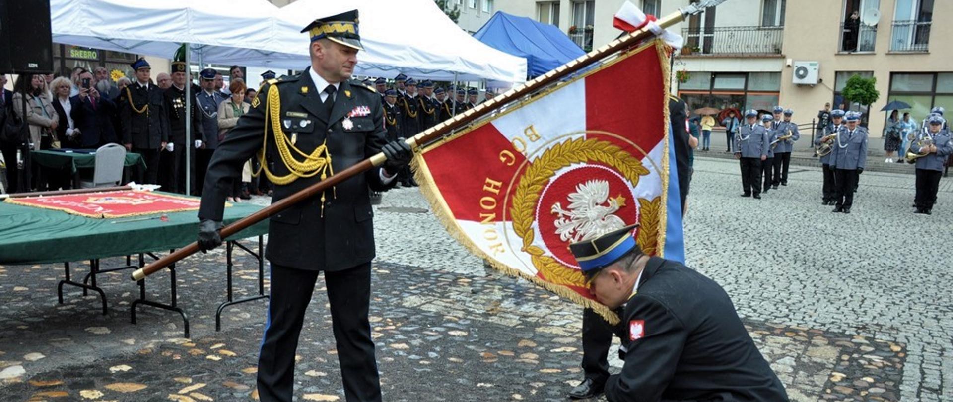 Oficerowie Państwowej Straży Pożarnej ze sztandarem w barwach narodowych