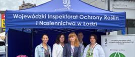 Namiot z napisem „Wojewódzki Inspektorat Ochrony Roślin i Nasiennictwa w Łodzi”. Przed namiotem stoją cztery osoby ustawione do wspólnego zdjęcia i uśmiechają się do aparatu.