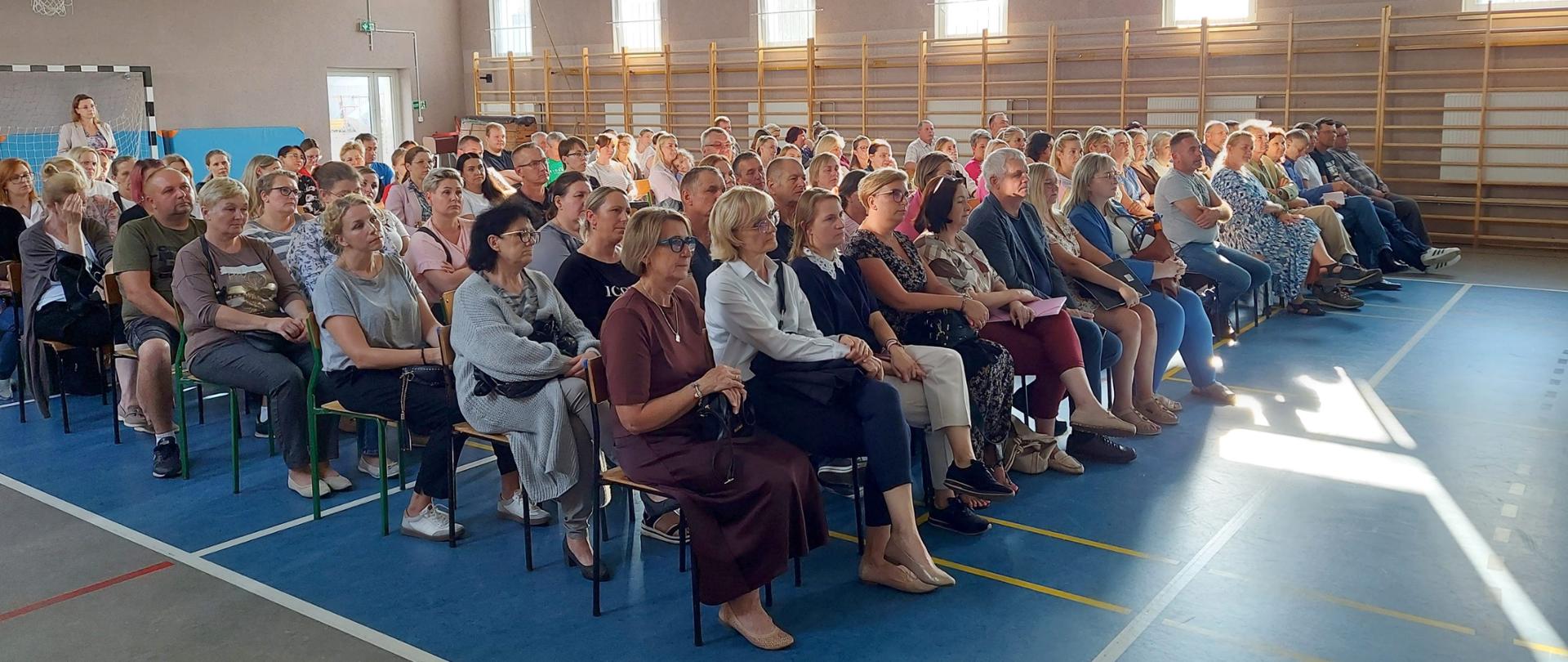 Nauczyciele i rodzice podczas spotkania w sali gimnastycznej