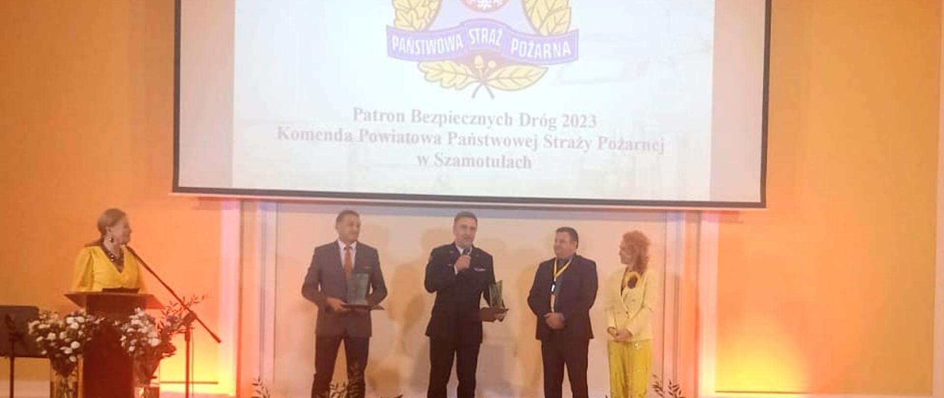 Widać Komendanta Powiatowego PSP Szamotuły i kilka osób po wręczeniu statuetki