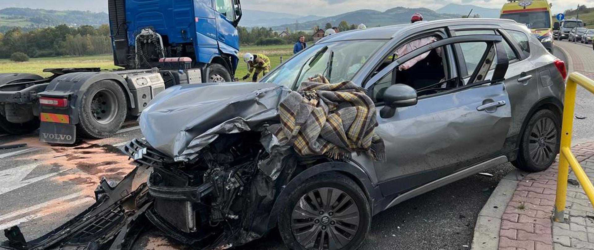 Rozbity samochód osobowy a w tle samochód ciężarowy