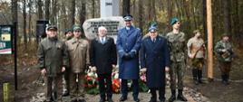 Obchody Święta Niepodległości w Tamie. Uczestnicy stoją i pozują do zdjęcia na tle pomnika. 