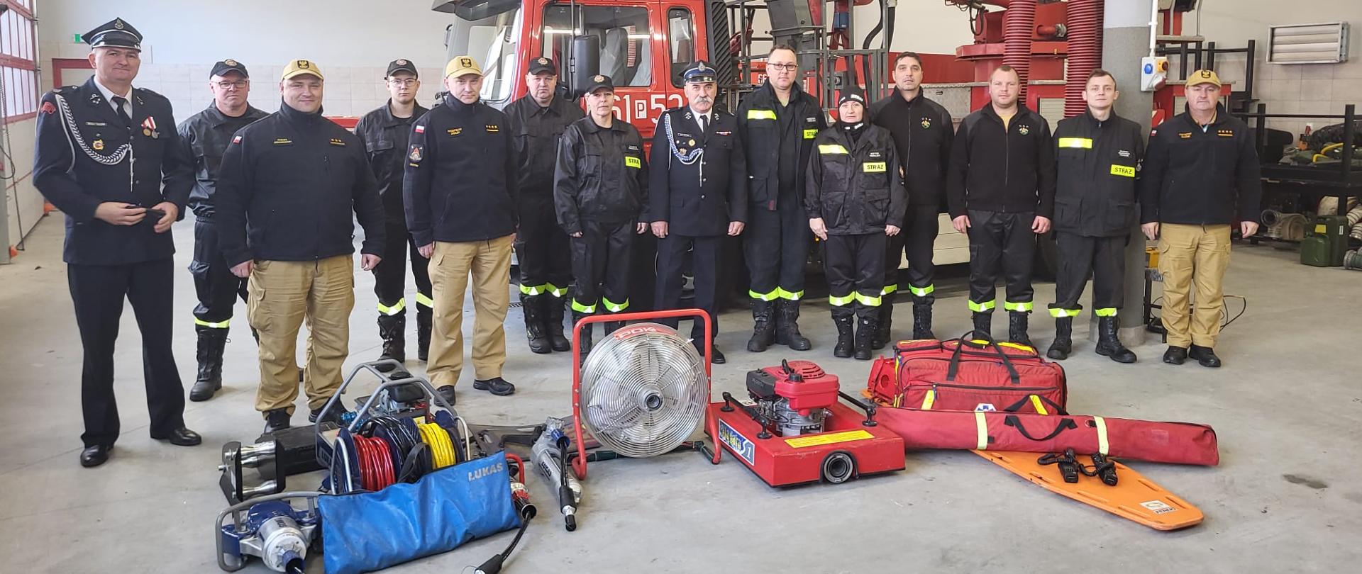Zdjęcie przedstawia strażaków a prze ich nogami leży sprzęt strażacki