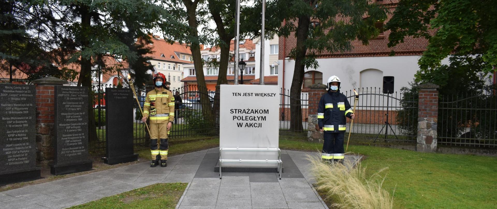Zdjęcie ukazuje dwóch strażaków pełniących wartę przy pomniku upamiętniającym strażaków poległych w akcji