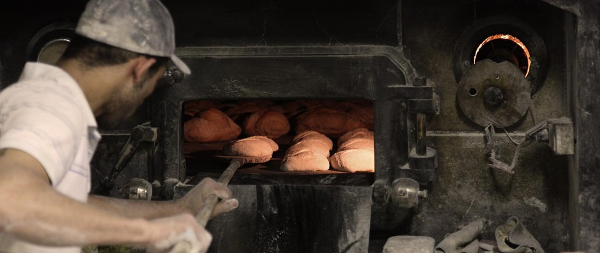 piekarz wkłada chleb do pieca