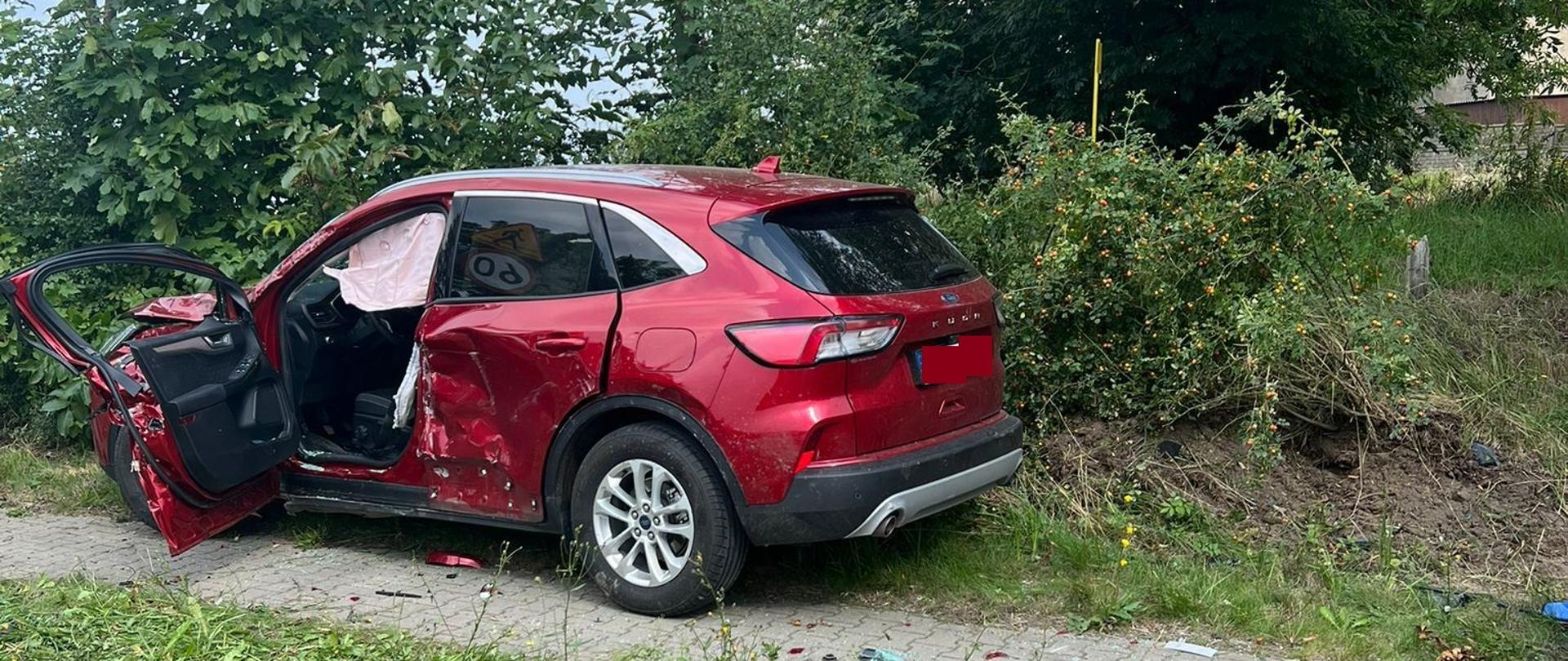 Bordowy samochód jest na poboczu blisko drzew