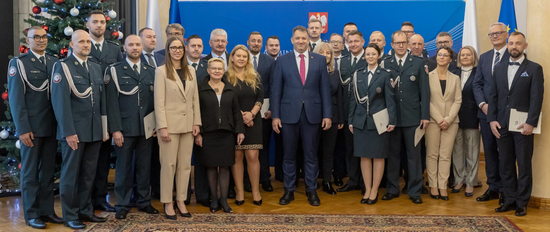 Szef KAS Marcin Łoboda oraz zastępcy szefa KAS Małgorzata Krok i Zbigniew Stawicki na wspólnym zdjęciu z pracownikami i funkcjonariuszami.