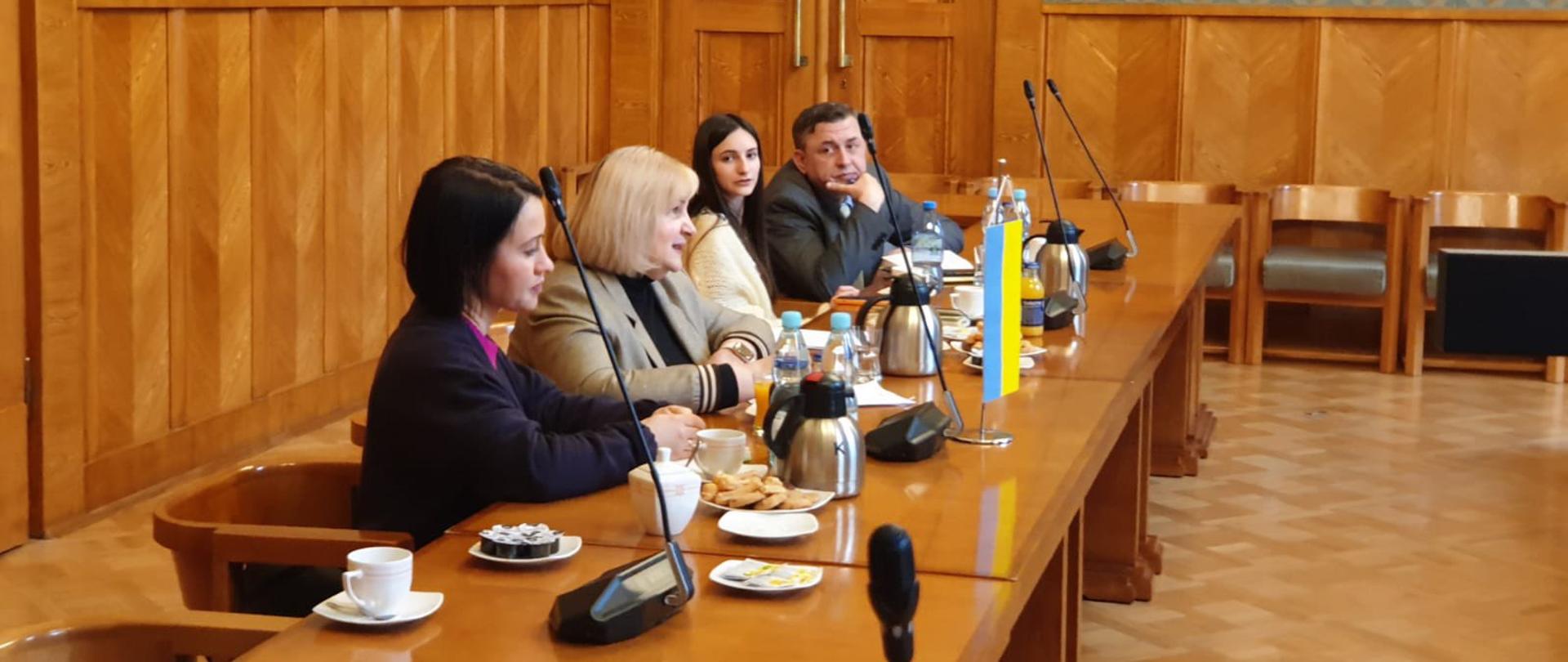 Uczestnicy spotkania siedzą i rozmawiają przy stole.