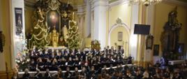 na zdjęciu w tle ołtarz w kościele na pierwszym planie orkiestra i chór uczniów Szkoły Muzycznej w Bydgoszczy