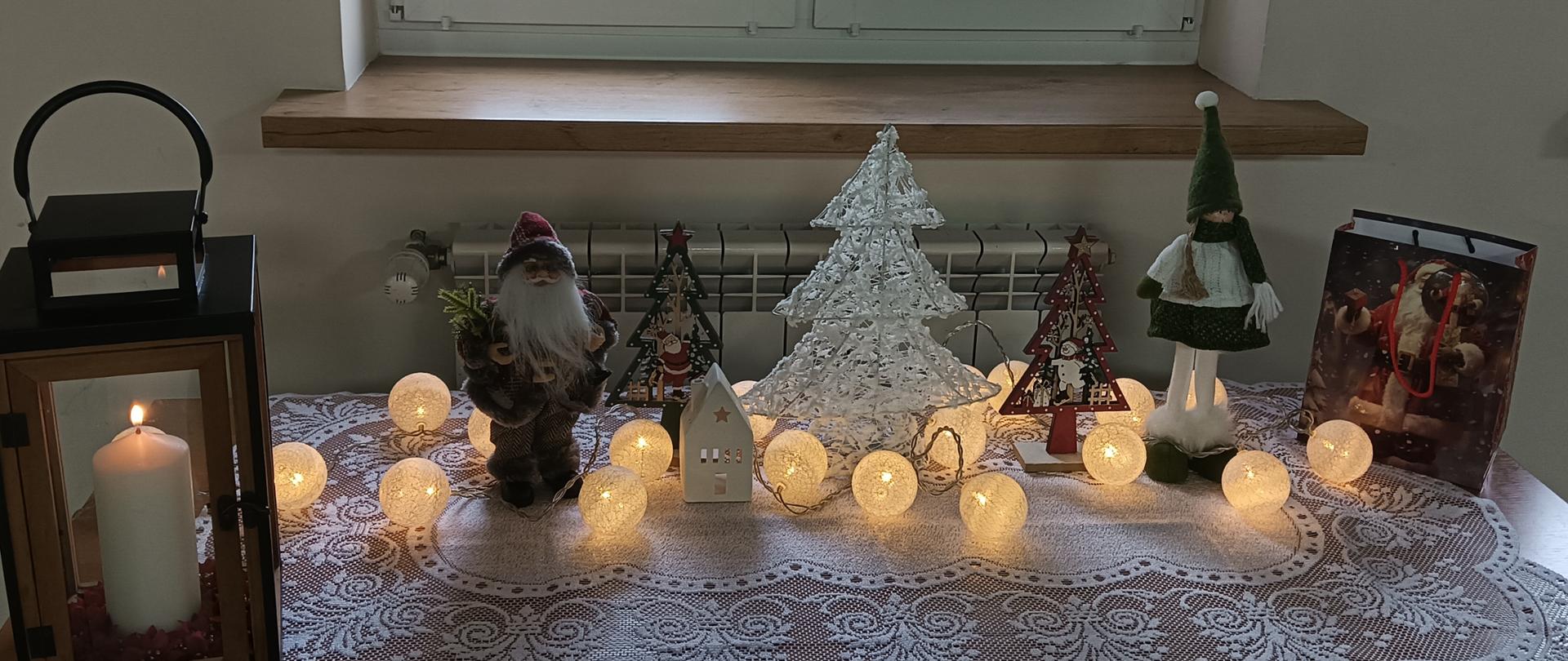 Dekoracja świąteczna, lampion, mikołaj choinki i skrzat na białym obrusie. 