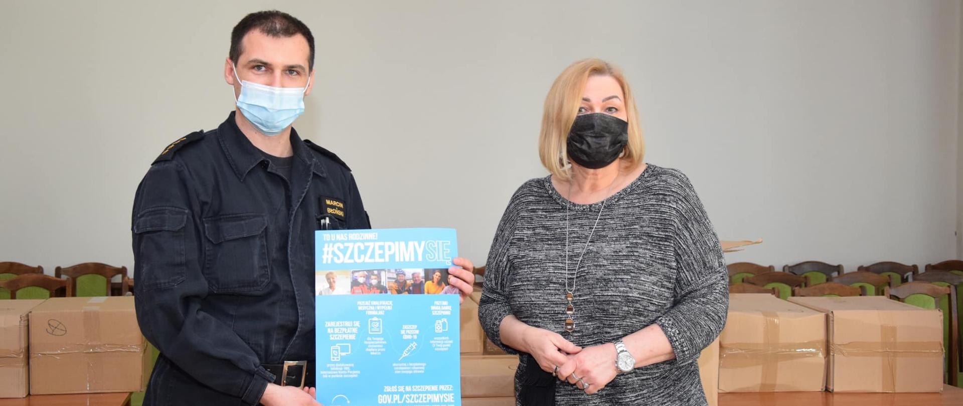 Na zdjęciu znajduje się zastępca komendanta wraz z przedstawicielem starostwa w czasie przekazania ulotek informacyjnych 